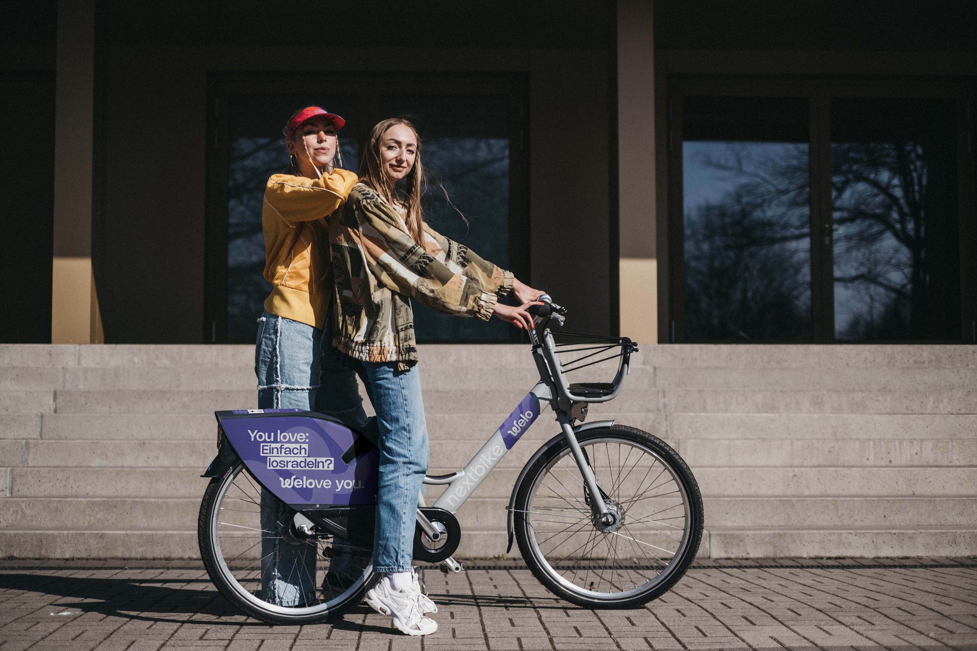 Two friends stand next to each other beside their welo rental bikes.